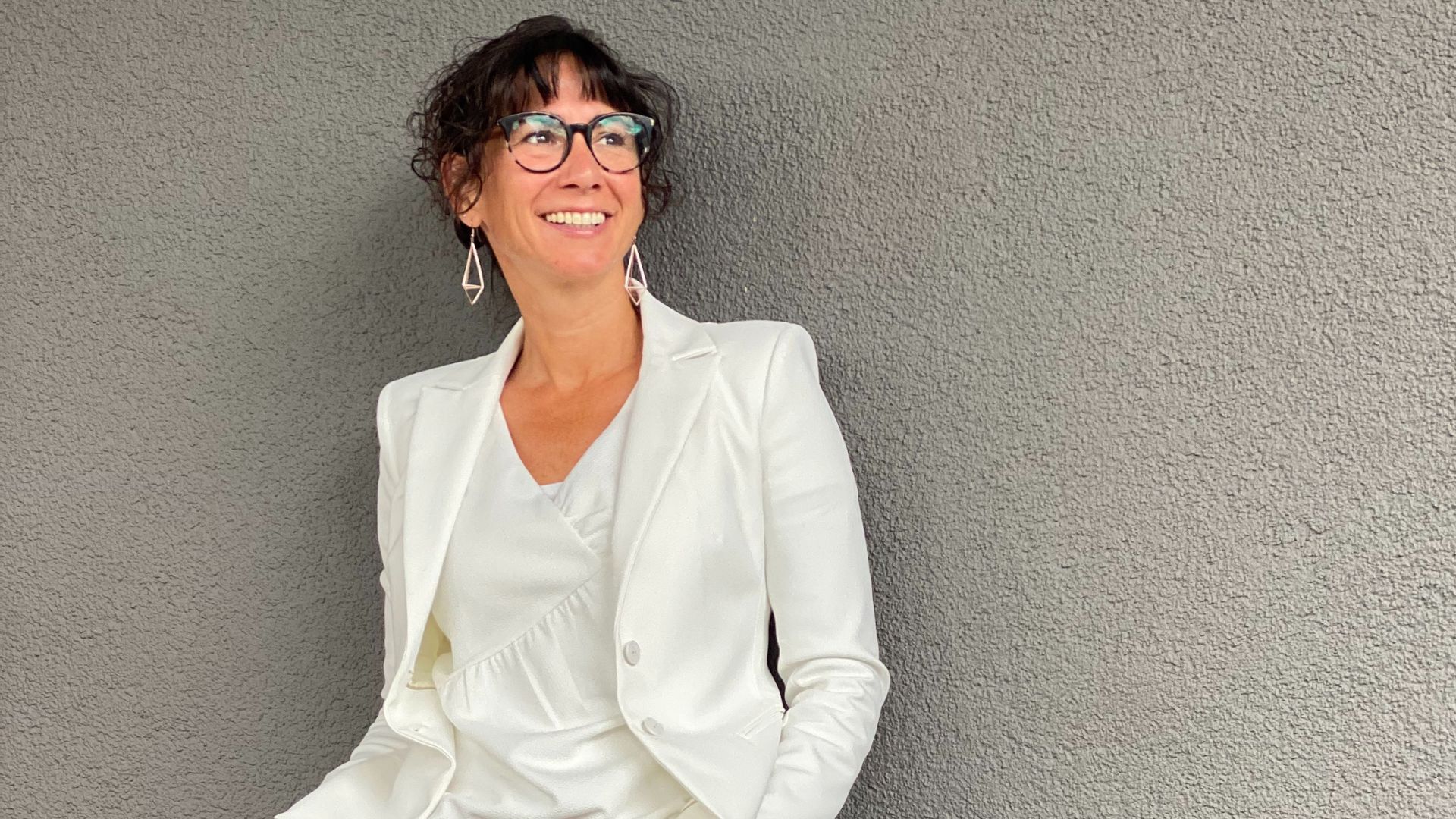 Claudia Potschigmann, Business Coach für Frauen, steht an einer Wand angelehnt und blickt in die Ferne