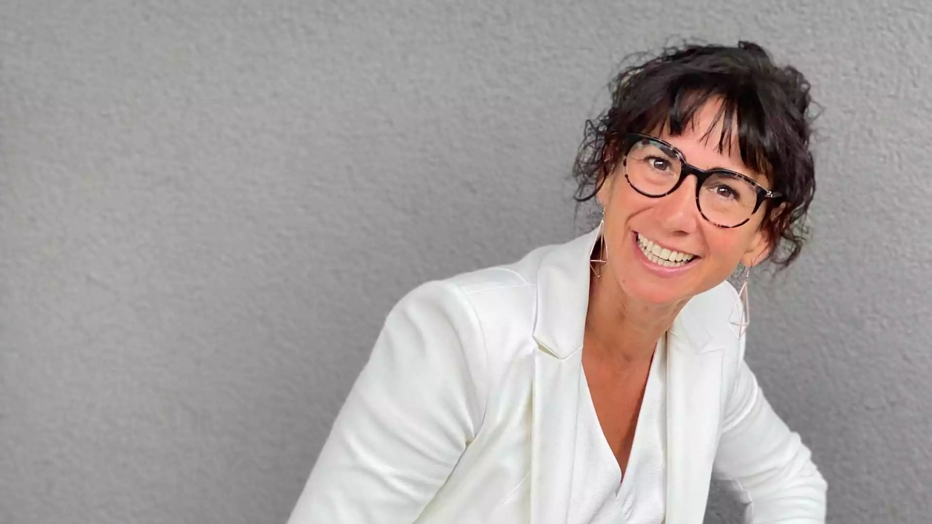 Claudia Potschigmann, Female Empowerment Coach, sitzt vor einer grauen Wand